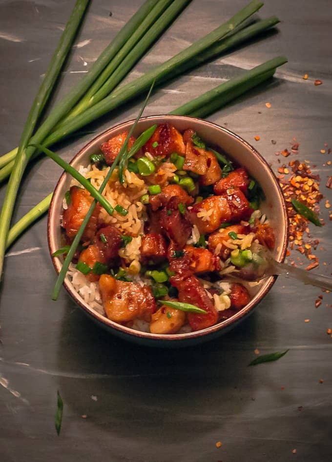 Sticky Chinese Pork Belly in bowl on back background with green onion