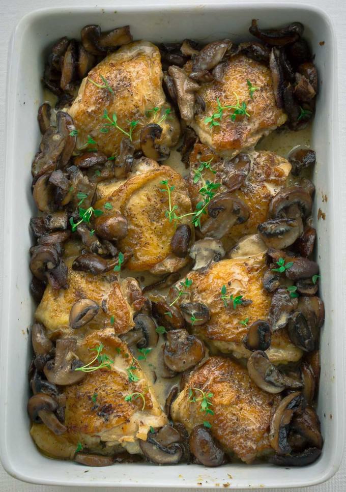 Rectagular white baking dish with 8 Crispy Roasted Chicken Thighs with Mushrooms and Cream Sauce 