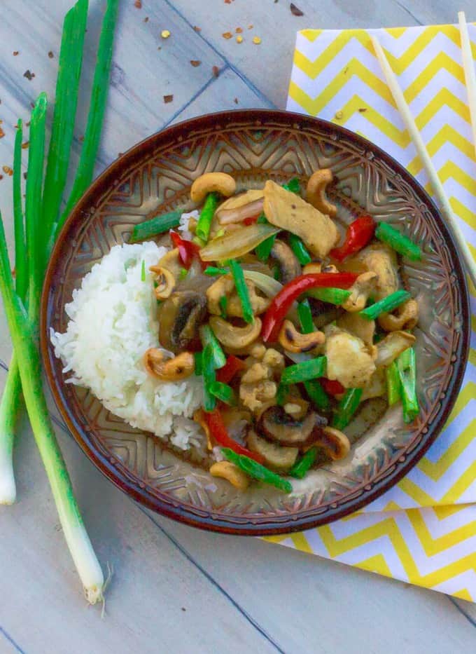 Thai Style Cashew Chicken on brown plate with yellow napkin and chopsticks