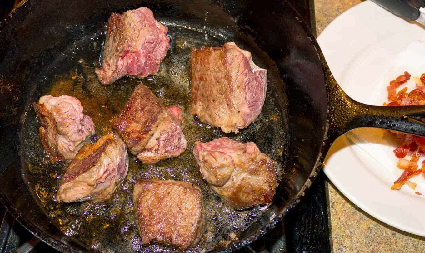 Chuck Roast pieces browning in a cast iron skillet