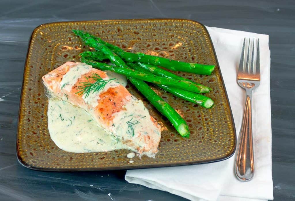 Easy Pan Seared Salmon with Creamy Dill Sauce on square plate with asparagus