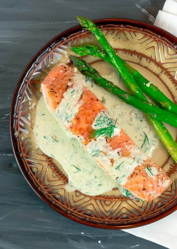 overhead view of Easy Pan Seared Salmon with Creamy Dill Sauce on round plate with asparagus