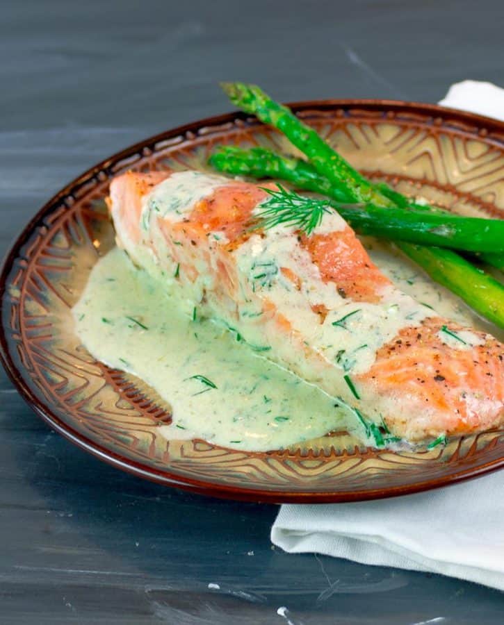 Easy Pan Seared Salmon with Creamy Dill Sauce on round plate with asparagus