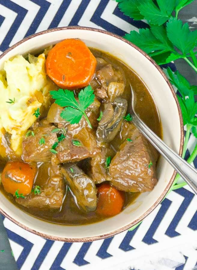 Beef and Guinness Stew in white bowl with mashed potatoes