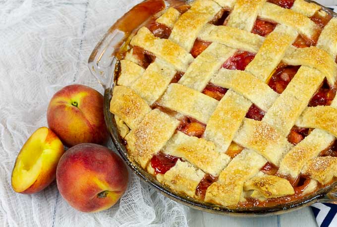 bottom left side of a Fresh Peach Pie With Homemade Crust with fresh peaches along side