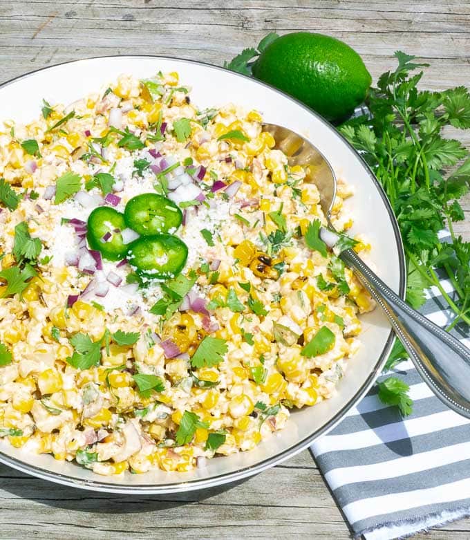 right side of a white bowl of Grilled Street Corn Salad with lime and cilantro