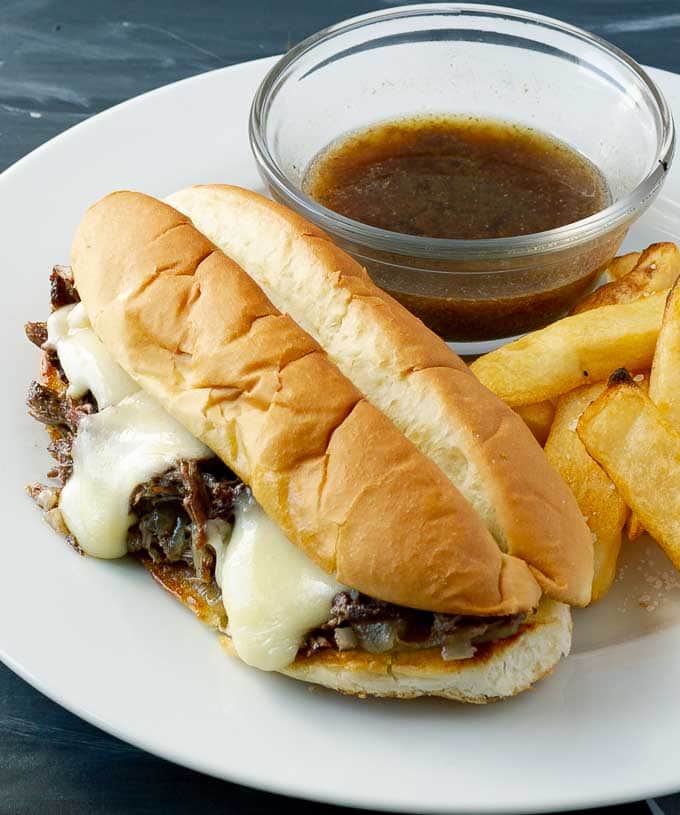 Crockpot French Dip Sandwich Recipe on white plate with fries and au jus