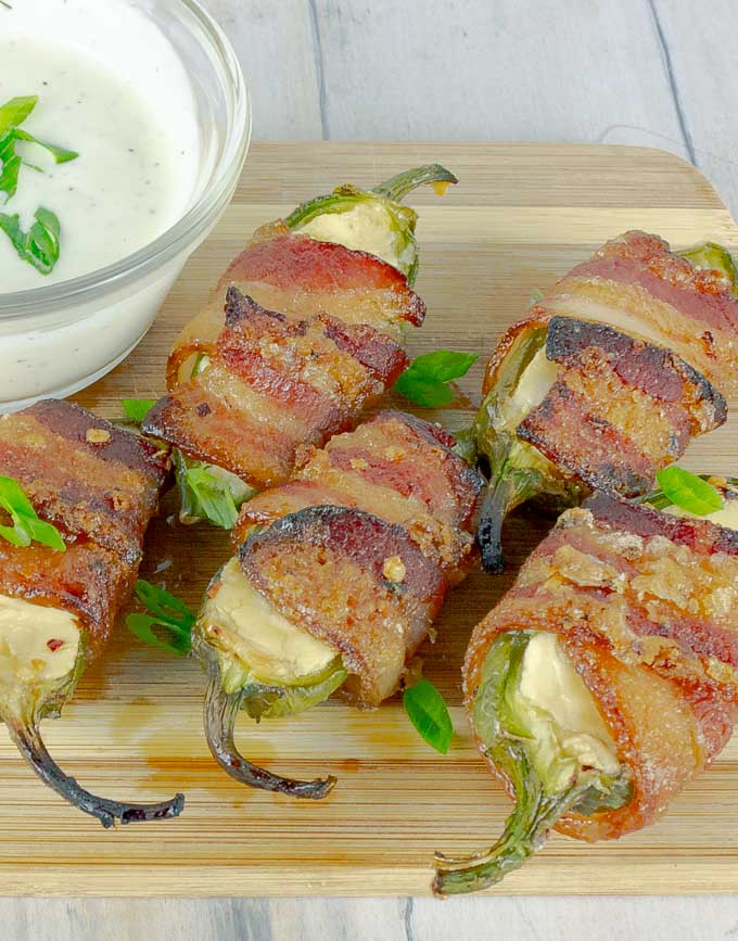 five Bourbon Candied Bacon Wrapped Jalapeno Poppers on wood with ranch