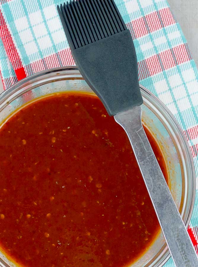 Homemade Chipotle Brown Sugar Barbecue Sauce in clear bowl with plaid napkin