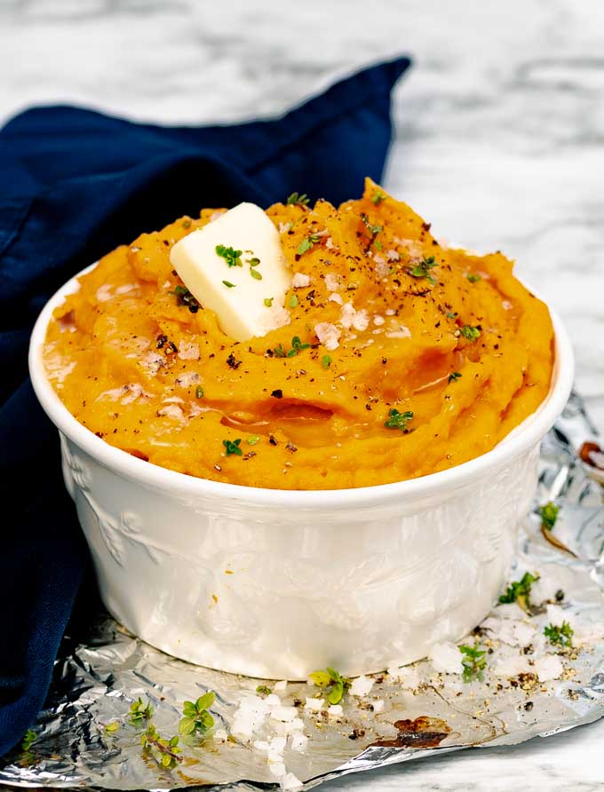 Roasted Savory Mashed Sweet Potatoes in a white bowl next to a blue napkin