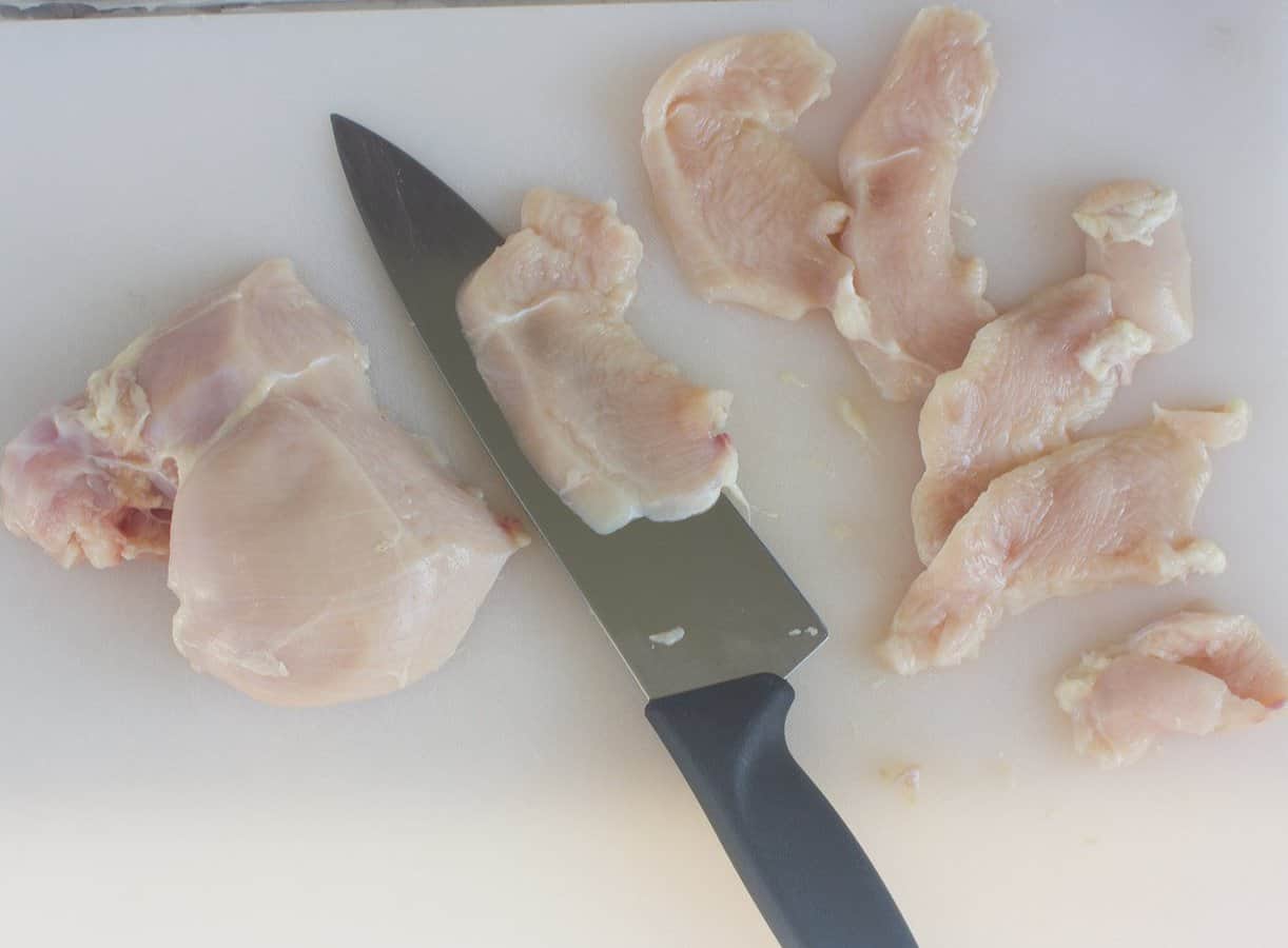 chicken breast for Thai Style Cashew Chicken being sliced at an angle and against the grain
