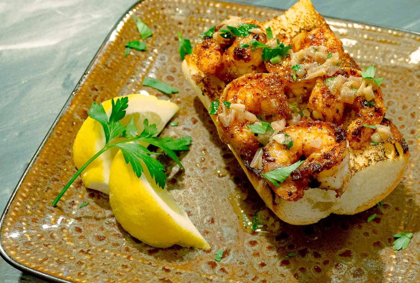 Spicy Shrimp Toasts with Lemon Garlic Butter shown at an angle on a brown square plate