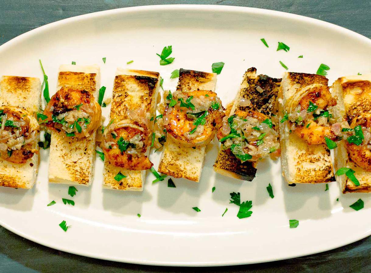 Spicy Shrimp Toasts with Lemon Garlic Butter shown on an oval white platter with parsley