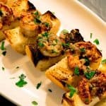 Spicy Shrimp Toasts with Lemon Garlic Butter shown at an angle on a white tray