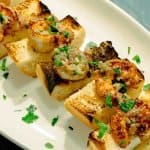 Spicy Shrimp Toasts with Lemon Garlic Butter shown on an oval white platter with parsley