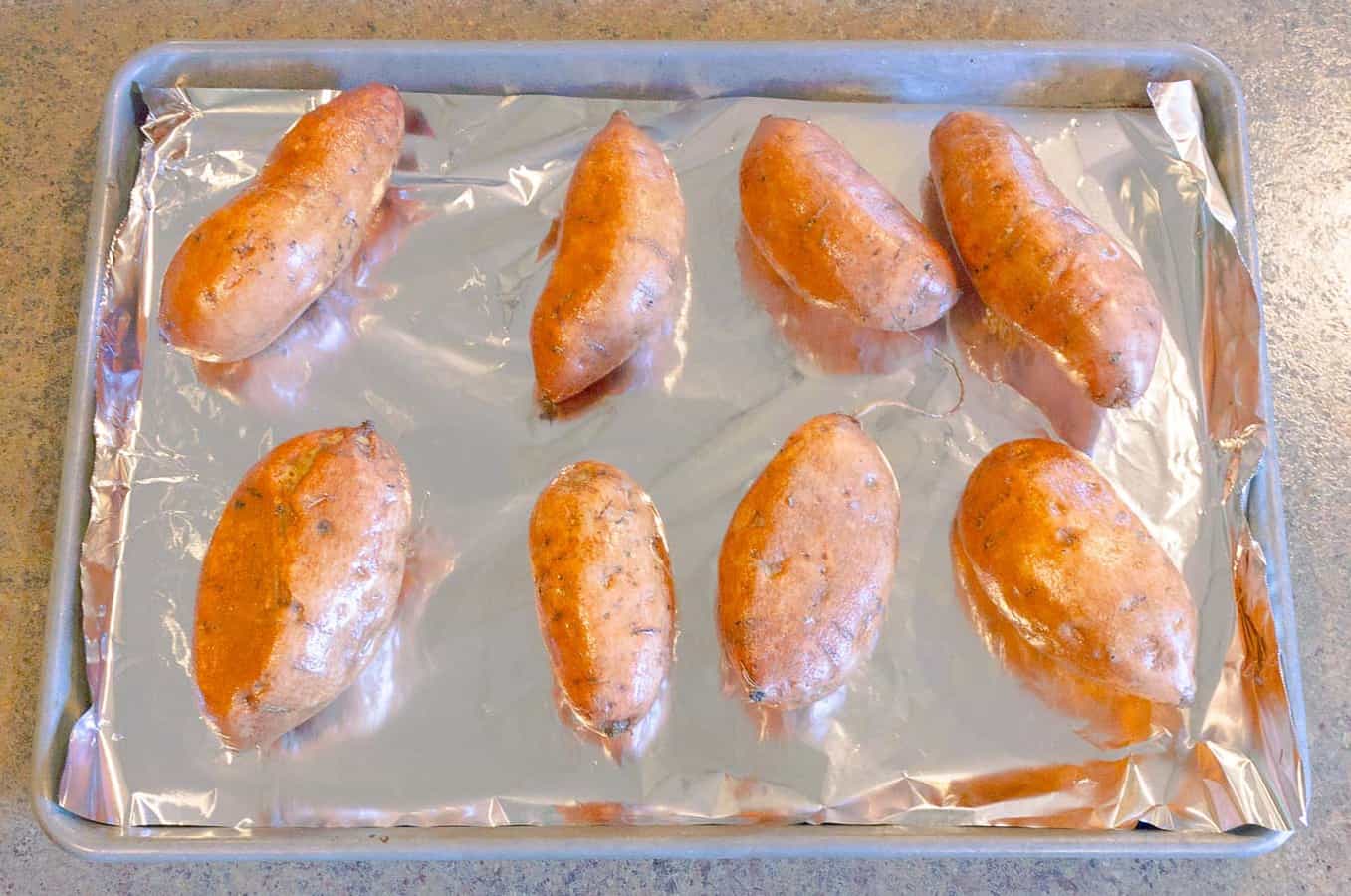 baked sweet potatoes on a foil lined pan ready to be bakes