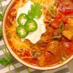 Instant Pot Pressure Cooker Red Pork Chili in a bowl with ganishings on a gray striped napkin.