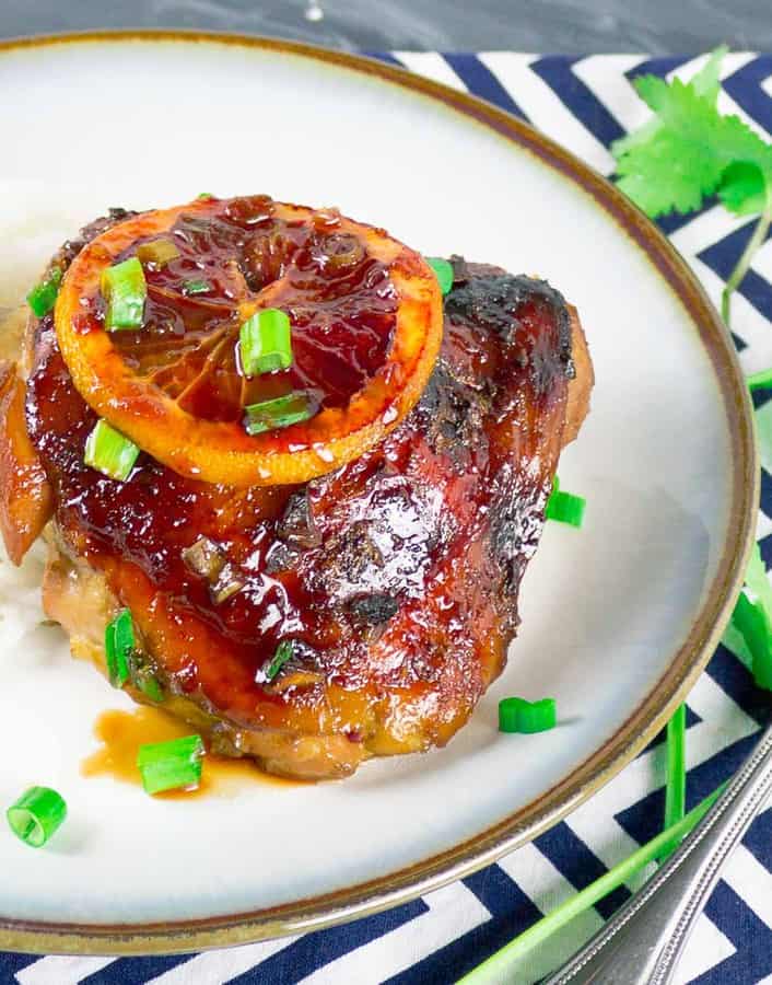 Sticky Asian Blood Orange Chicken on white plate with green onion garnish