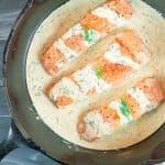 3 pieces of Easy Pan Seared Salmon with Creamy Dill Sauce in a cst iron skillet