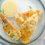 3 Healthy Buttermilk Baked Chicken Strips on white plate with honey mustard