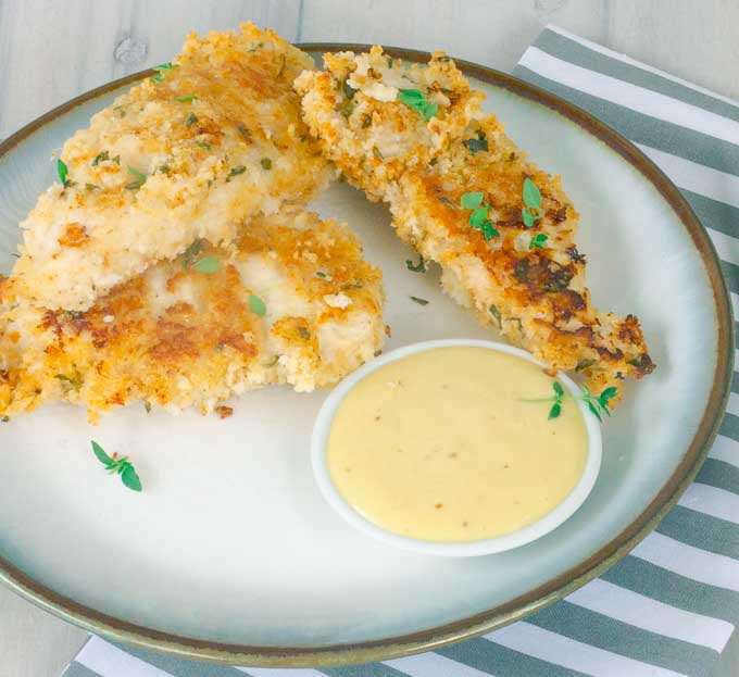 3 Healthy Buttermilk Baked Chicken Strips on white plate with honey mustard