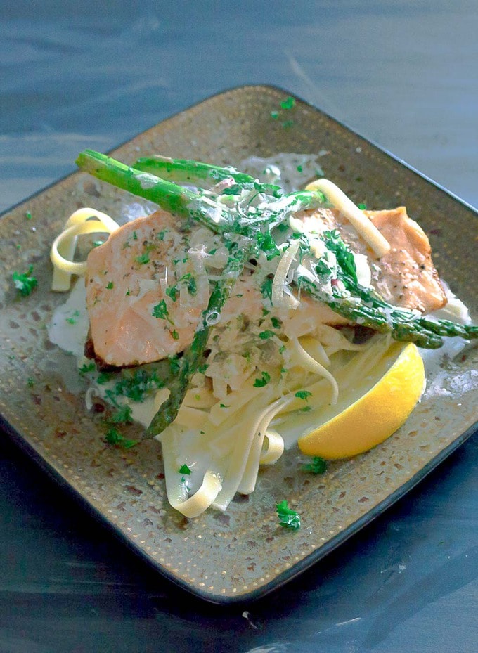 Salmon with Garlic Cream Sauce on square plate with asparagus and pasta