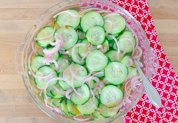 Pickled Cucumber and Red Onion Salad in clear bowl on a red cloth