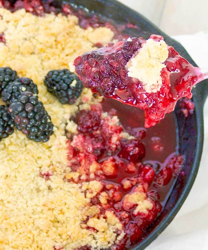 a spoonfull of Cast Iron Skillet Blackberry Crumble with the remainder of the crumble in the background