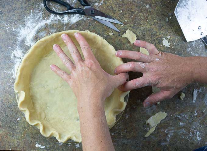 using finger tips to pinch and tuck a scapped crust edge