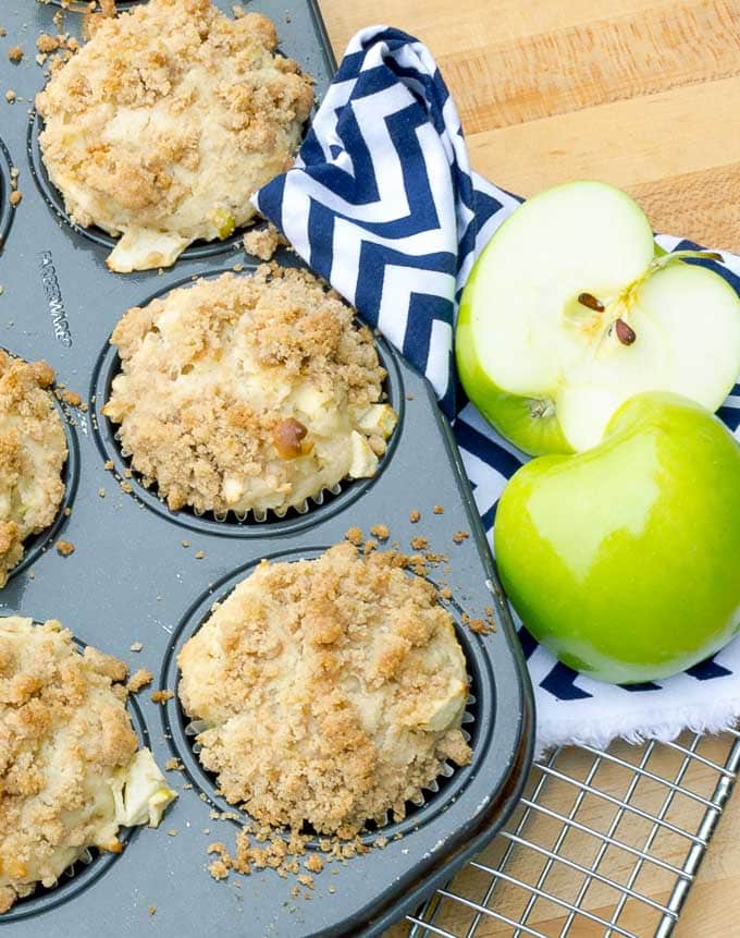 Apple Streusel Muffins in tin with blue napkin and apple