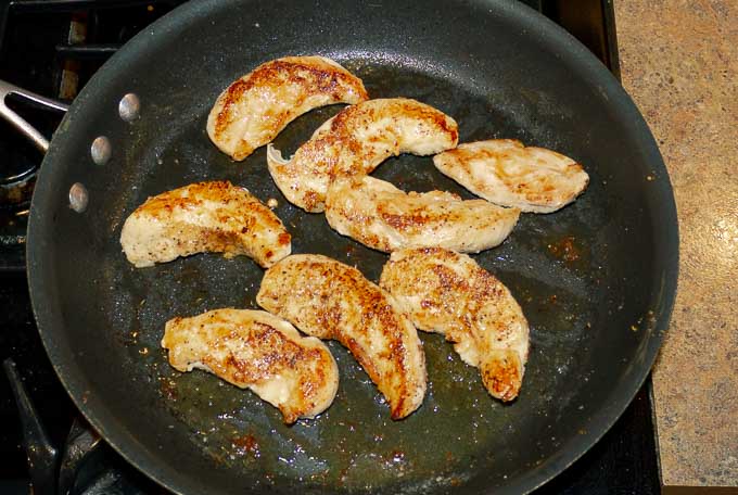 chicken tenderloins being seared in hot skillet