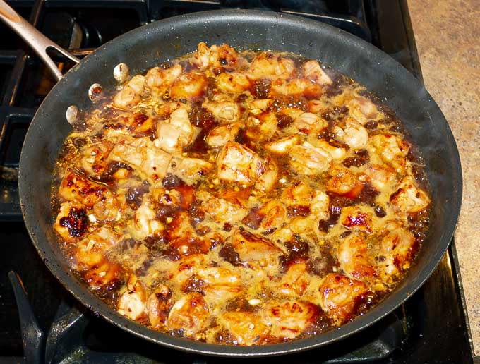 Sticky Orange Chicken Recipe bubbling in a pan with sauce