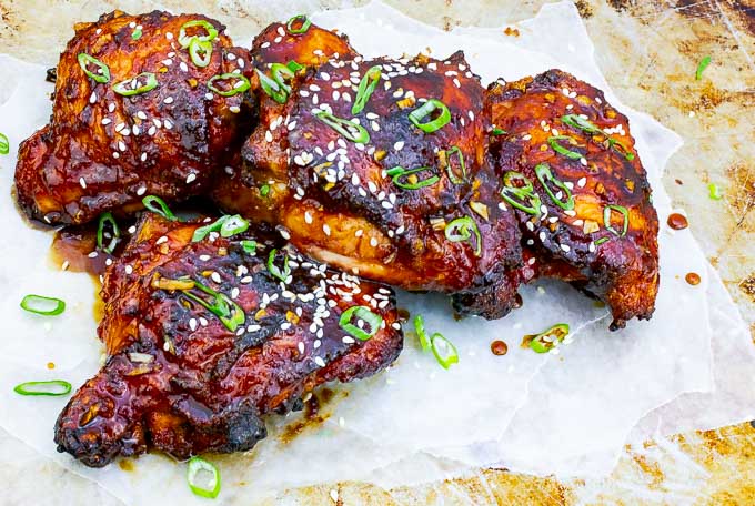 four Sticky Asian Grilled Chicken Thighs on white  and metal background