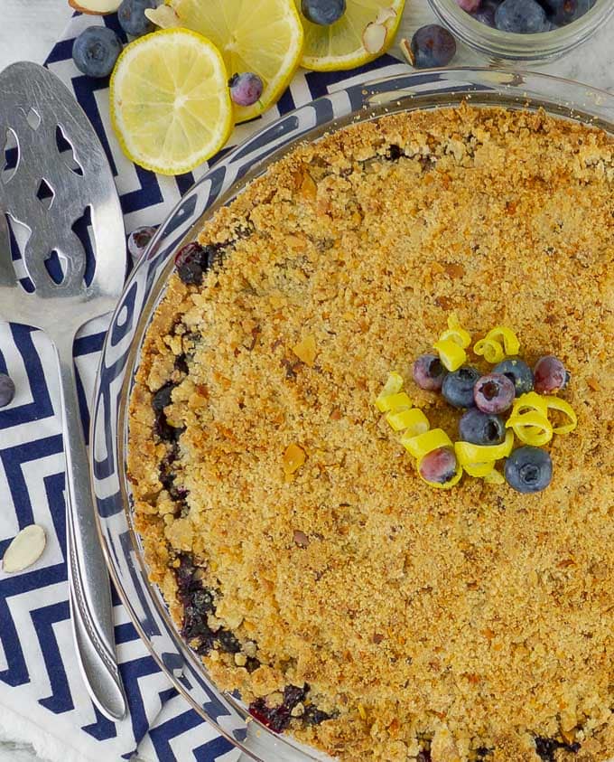 half of a Fresh Blueberry Almond Crumb Pie with lemon slices and blueberries