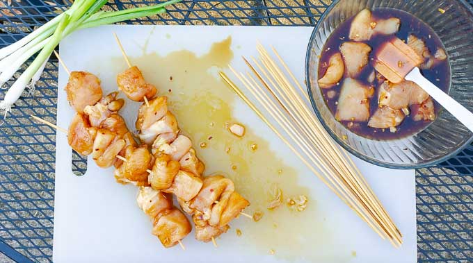 three raw Grilled Asian Chicken Kabobs on a white cutting board
