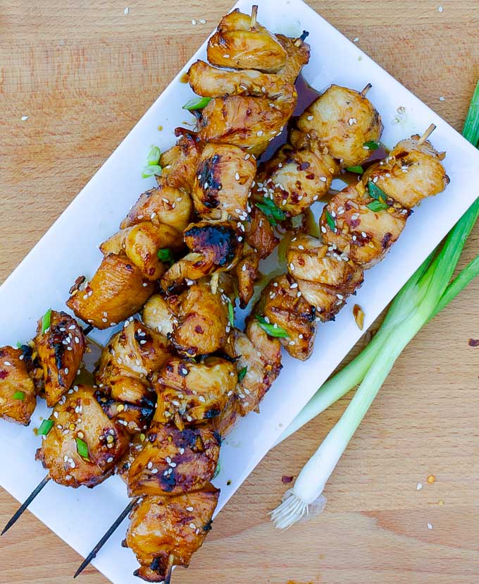 four Grilled Asian Chicken Kabobs on a white platter