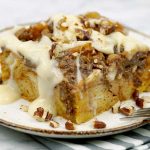 a slice of Pumpkin Pecan Custard Bread Pudding on a white place with frosting drizzle