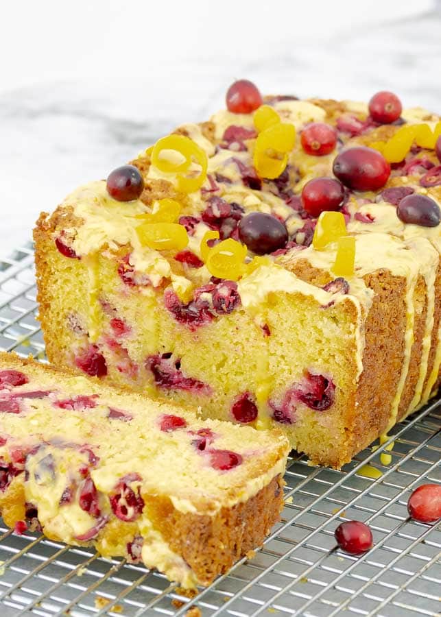 Orange Cranberry Pound Cake sliced open with drizzling glaze on wire rack
