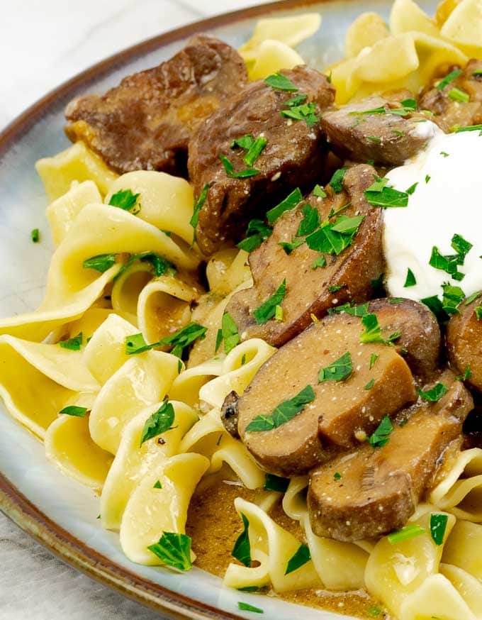 plate of Slow Cooker Beef Stroganoff Recipe From Scratch with a dollop of sour cream