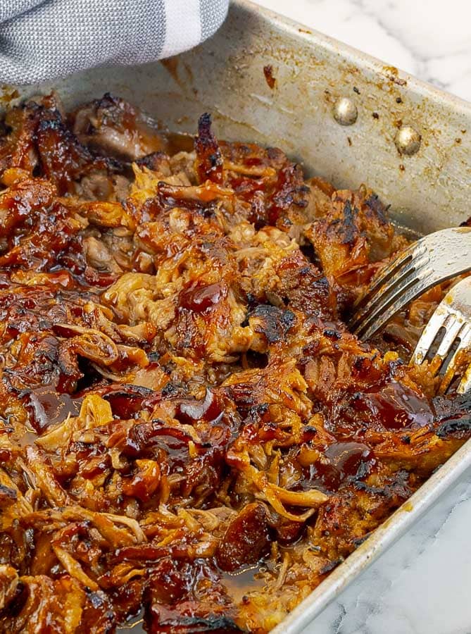 Barbecued Pulled Pork shredded in a baking pan with sauce