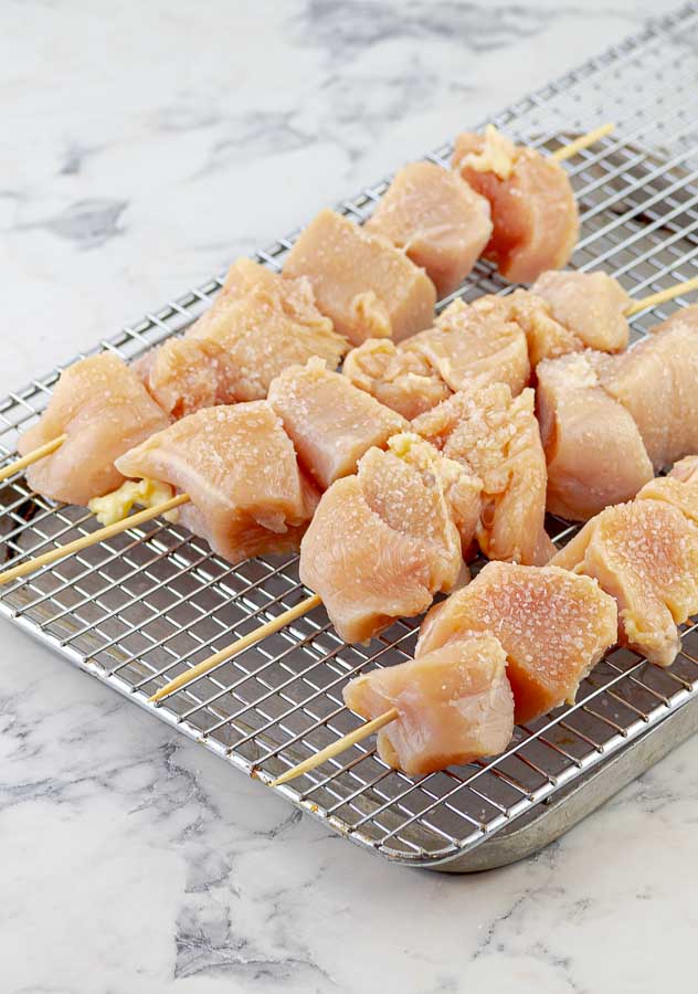uncooked chicken on skewers with salt or dry brine