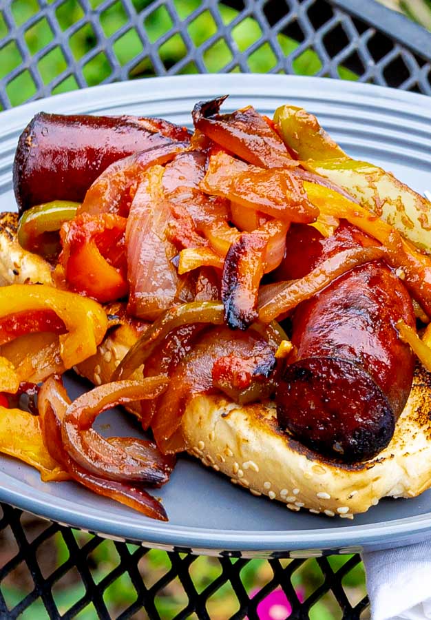 Grilled Sausage with Peppers and Onions on a bun on a gray plate