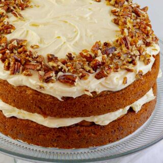 classic carrot cake recipe with cream cheese icing viewed from the side on a glass plate