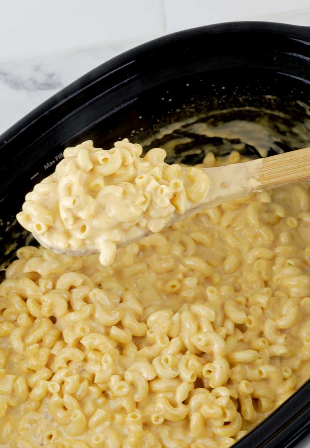 wooden spoon holding Extra Creamy Slow Cooker Macaroni and Cheese