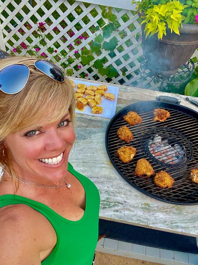 Jennifer grilling Italian chicken thighs on a 26" weber kettle grill