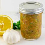mason jar of Homemade Zesty Italian Dressing with a lemon, garlic, and parsley