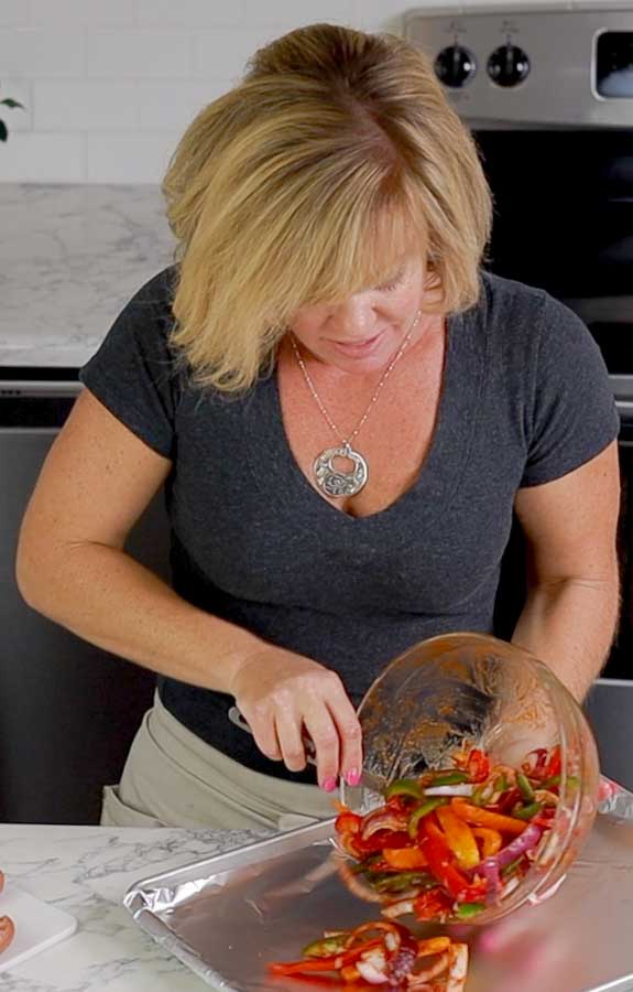 Jennifer pouring peppers on baking sheet