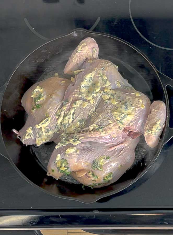 Spatchcock Chicken with Sage Brown Butter searing in a cast iron skillet