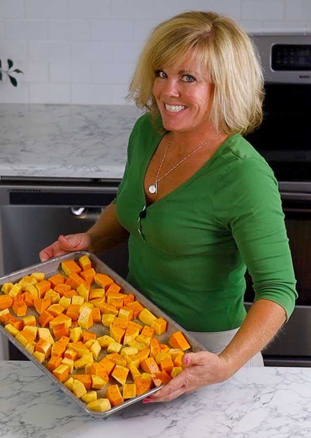 Jennifer holding baking sheet of squash ready to go into the oven