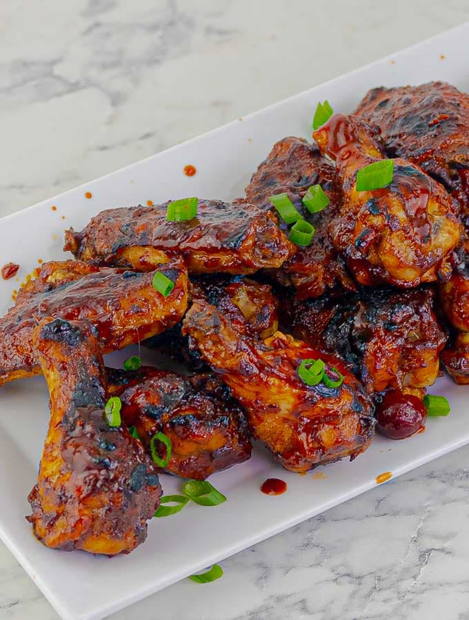 white rectangular plate of barbecue wings with green onions